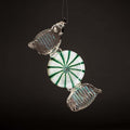 Decorative candy ornament with green and white design on a black background