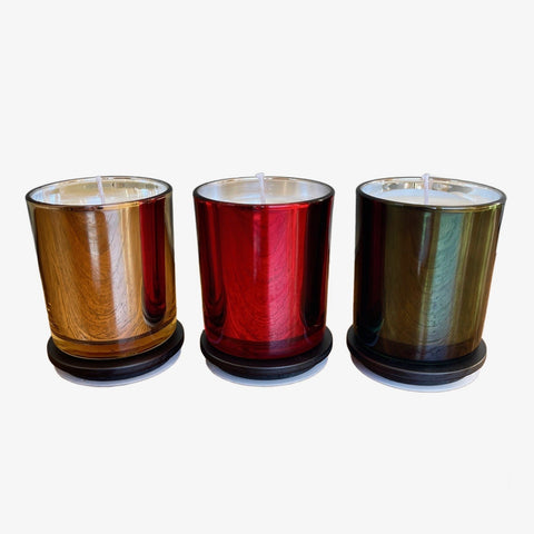 Three cylindrical candles with different color finishes on a white background