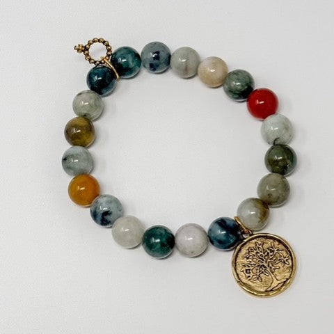 Multicolored beaded bracelet with a gold tree of life charm on a white background